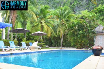 Luxury outdoor swimming pool area with lounge chairs, umbrellas, and lush greenery