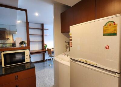 A kitchen with a refrigerator, microwave, and washing machine