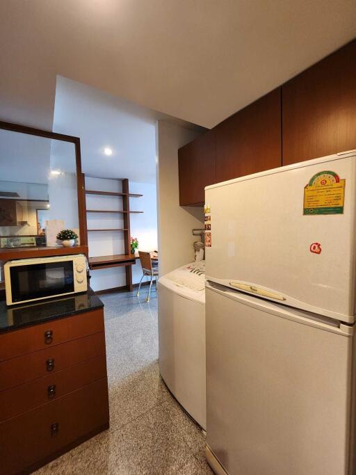 A kitchen with a refrigerator, microwave, and washing machine