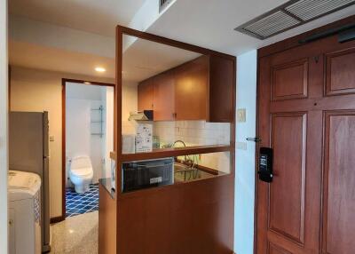 Compact kitchen with adjacent bathroom and wooden door