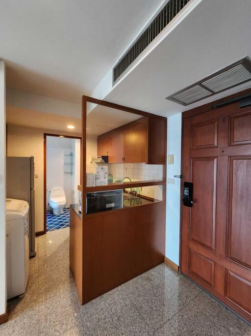 Compact kitchen with adjacent bathroom and wooden door