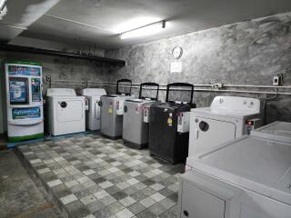 A spacious laundry room with multiple washing machines and coin-operated detergent dispensers.