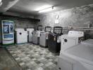 A spacious laundry room with multiple washing machines and coin-operated detergent dispensers.