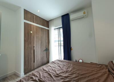 Modern bedroom with a large window, wooden wardrobe, and air conditioning unit
