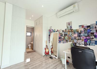 Modern bedroom with desk, air conditioner, and wall decorated with photos