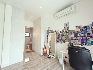 Modern bedroom with desk, air conditioner, and wall decorated with photos