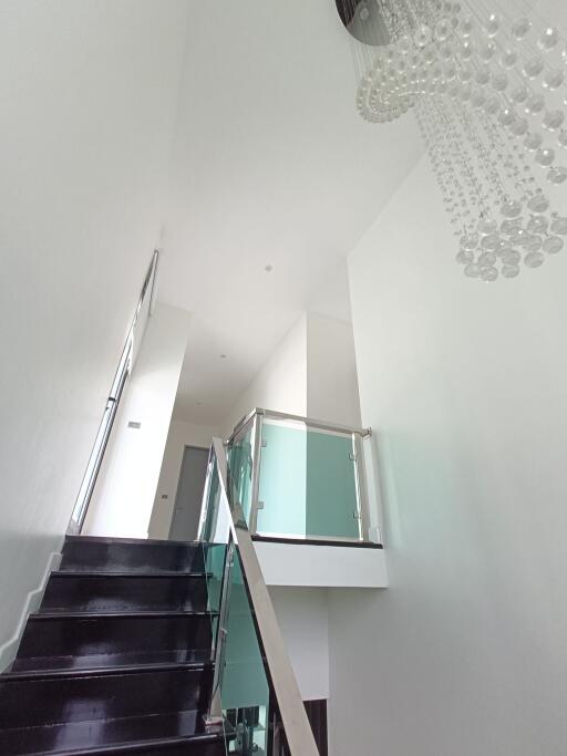Interior staircase with glass railing and chandelier