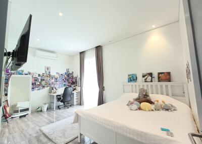 Spacious bedroom with a large bed, wall-mounted TV, desk area, and natural light