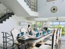 Modern dining room with table set for meal, staircase, and large windows