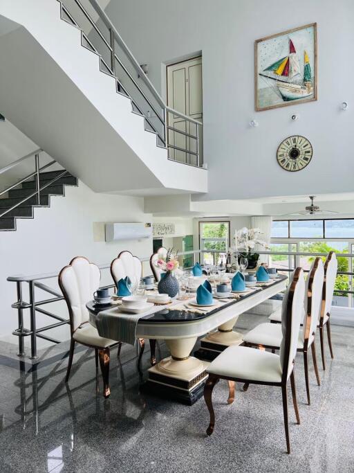 Modern dining room with table set for meal, staircase, and large windows
