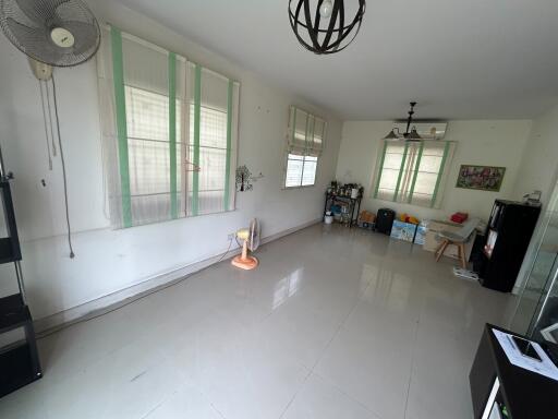 Spacious living room with windows, tile flooring, and some furnishings