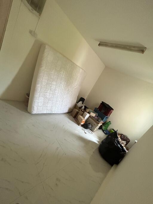 Unfurnished room with belongings and a mattress against the wall