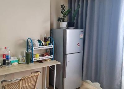 Small kitchen area with refrigerator, table, chair, and plant