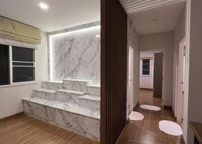 Modern living area with wooden flooring and marble-featured wall