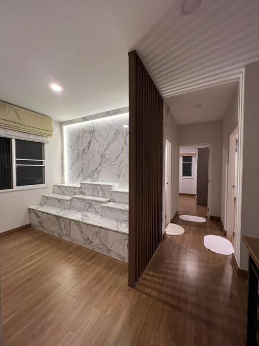Modern living area with wooden flooring and marble-featured wall