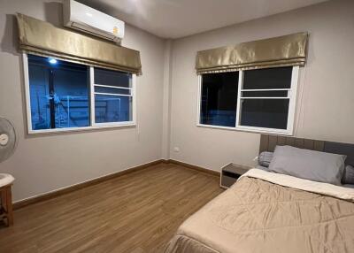 A well-lit bedroom with wooden flooring, double bed, and air conditioner