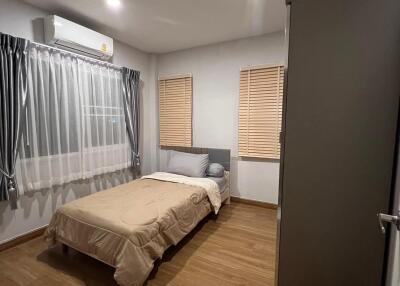 Modern bedroom with wooden flooring, single bed, gray wardrobe, and air conditioning