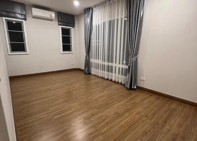 A spacious and well-lit bedroom with hardwood floors and large windows.