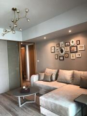 Modern living room with beige sectional sofa, decorative wall art, and unique light fixture