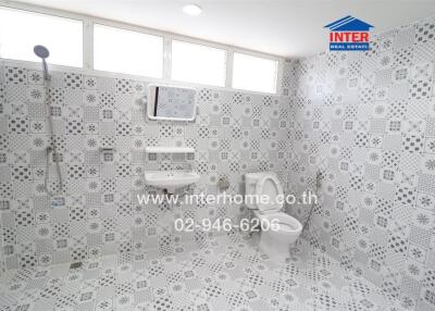 Spacious tiled bathroom with toilet, sink, and shower