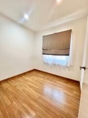 Empty bedroom with wooden flooring and window with blinds