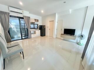 Modern living room with tiled flooring, glass door to balcony, TV, and air conditioning