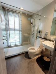 Modern bathroom with glass shower, toilet, sink, and vanity