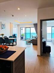 Modern open-plan living area with dining table, kitchen, and ocean view