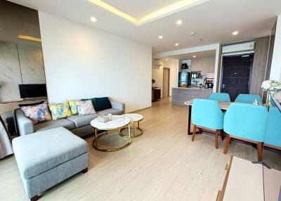 Modern living area with an open plan design, featuring light wood flooring, cozy furniture, and a dining space