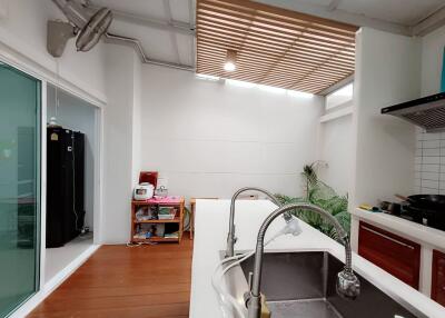 Modern kitchen with white countertops and a sink, adjacent to a well-lit dining area with greenery