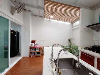 Modern kitchen with white countertops and a sink, adjacent to a well-lit dining area with greenery