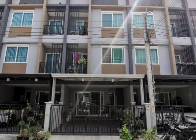 Three-story residential building with balconies and parking space