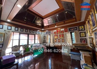 Luxurious living room with large windows, high ceiling, and framed artwork