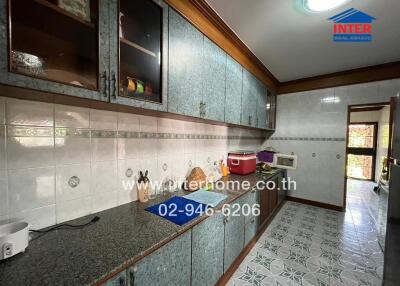 Spacious kitchen with tiled walls and flooring, ample cabinet storage, and modern countertop