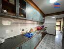 Spacious kitchen with tiled walls and flooring, ample cabinet storage, and modern countertop