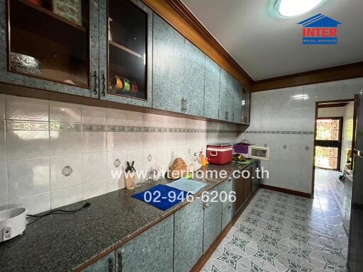 Spacious kitchen with tiled walls and flooring, ample cabinet storage, and modern countertop