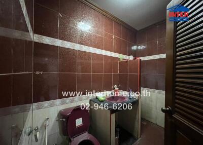 A small bathroom with dark brown tiles and essential fittings