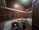 A small bathroom with dark brown tiles and essential fittings