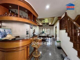 Spacious living room with a wooden bar, staircase, and ceiling fan.