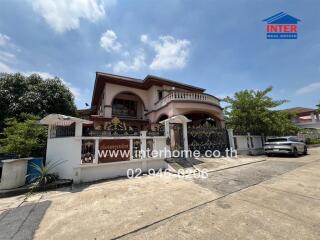 Two-story house with a balcony, gated entrance, and driveway