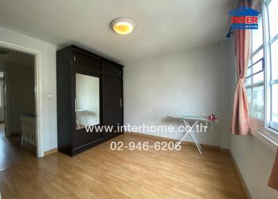 Spacious bedroom with wooden flooring, large wardrobe, and ample natural light.