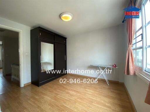 Spacious bedroom with wooden flooring, large wardrobe, and ample natural light.