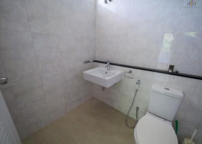 modern bathroom with a toilet, sink, and tiled walls