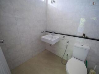 modern bathroom with a toilet, sink, and tiled walls
