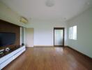 Spacious living room with a wooden floor, TV console, and air conditioning