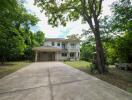 Two-story house with driveway and surrounding trees