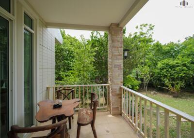 Balcony with wooden furniture and view of garden