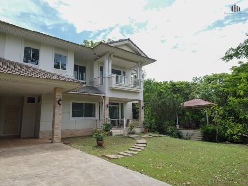 Front view of a two-story house with a garden and gazebo