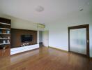 Spacious living room with wooden flooring, built-in shelves, and a wall-mounted TV.