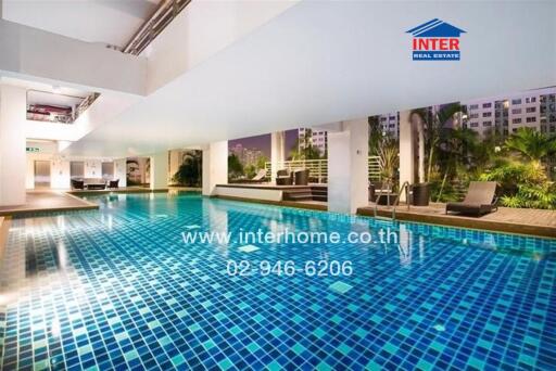 Indoor swimming pool with lounge chairs and greenery